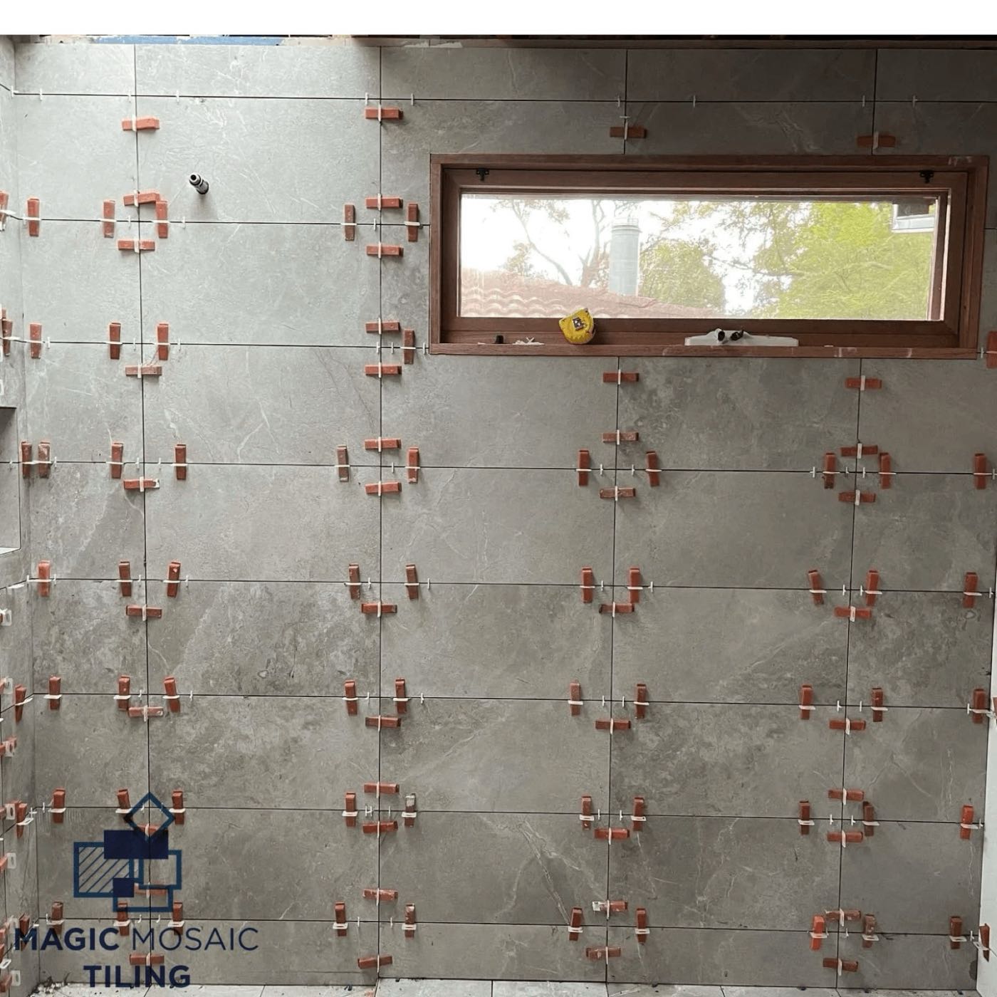 Levelling clips holding large wall tiles flush