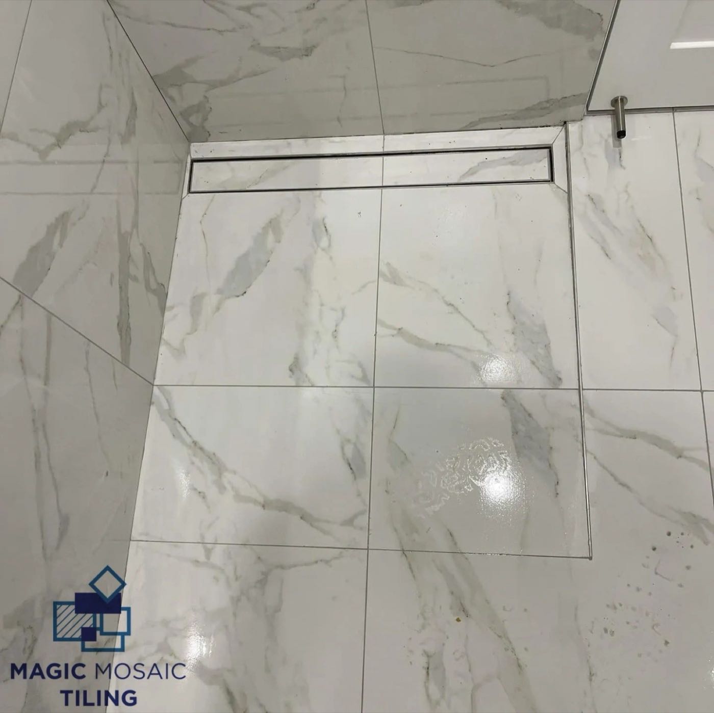 Marble-look shower floor falling to a strip drain