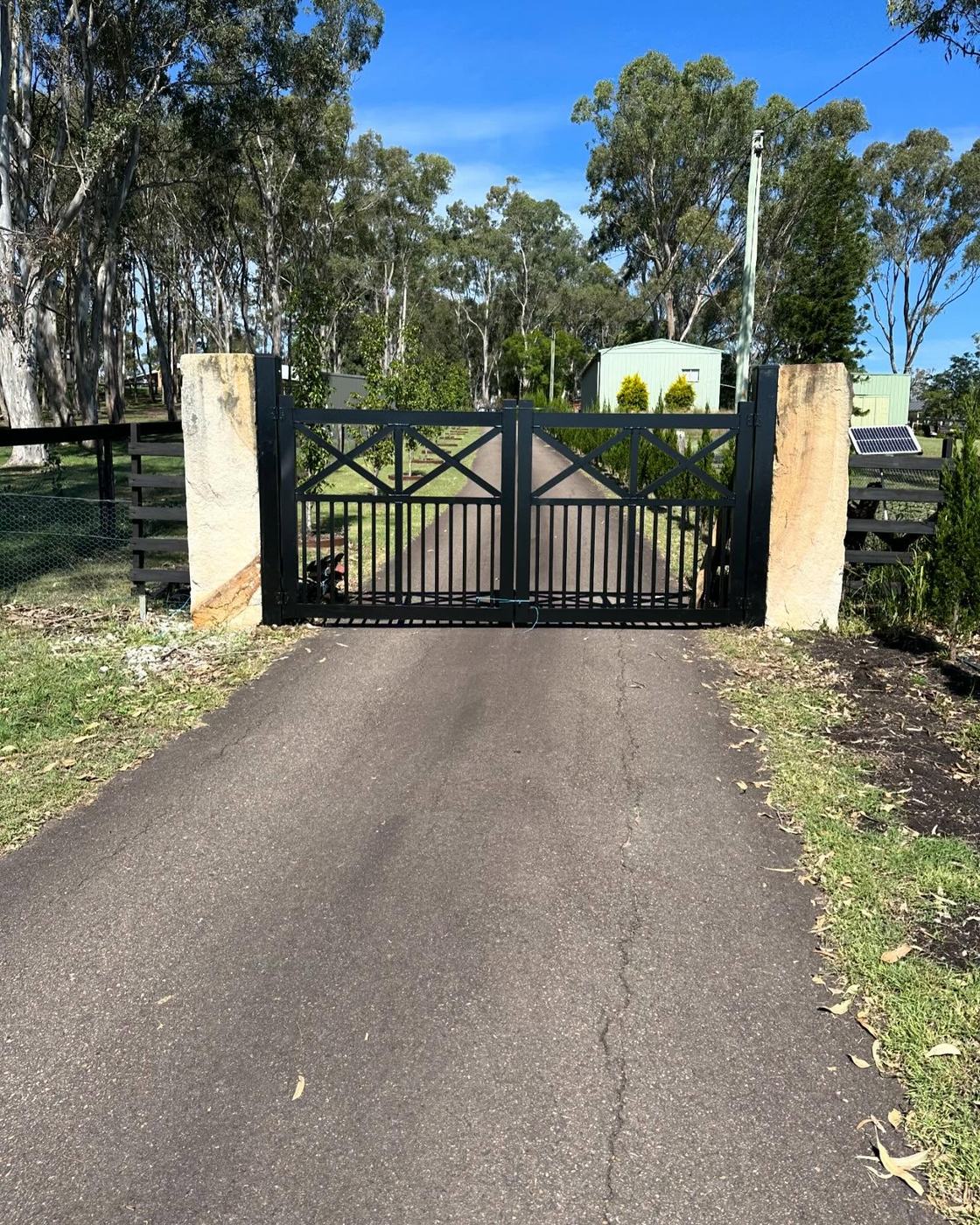 Black tubular double gates between sandstone pillars